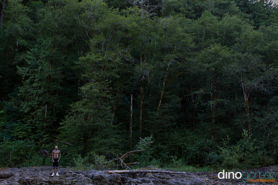 Tattooed Man Standing On The Rocks In Front Of A Forest In Portland By Photographer In Portland Dino Gomez