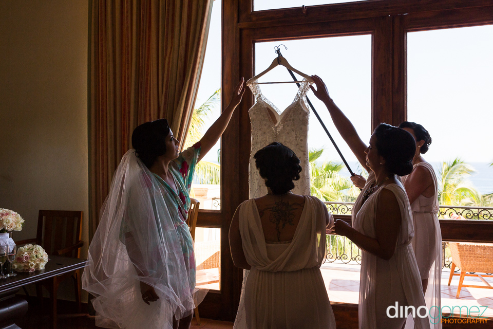 The Bride Removing Her Hanging Dress With Help From Her Bridesmaids Before The Wedding