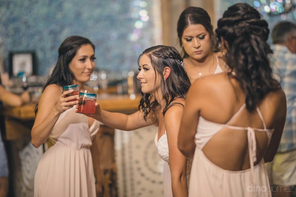 The Bride Is Standing Among Her Girl Friends And Is Sharing A Glass Of Drink With Them At The Evening Party- Nicole & Ryan