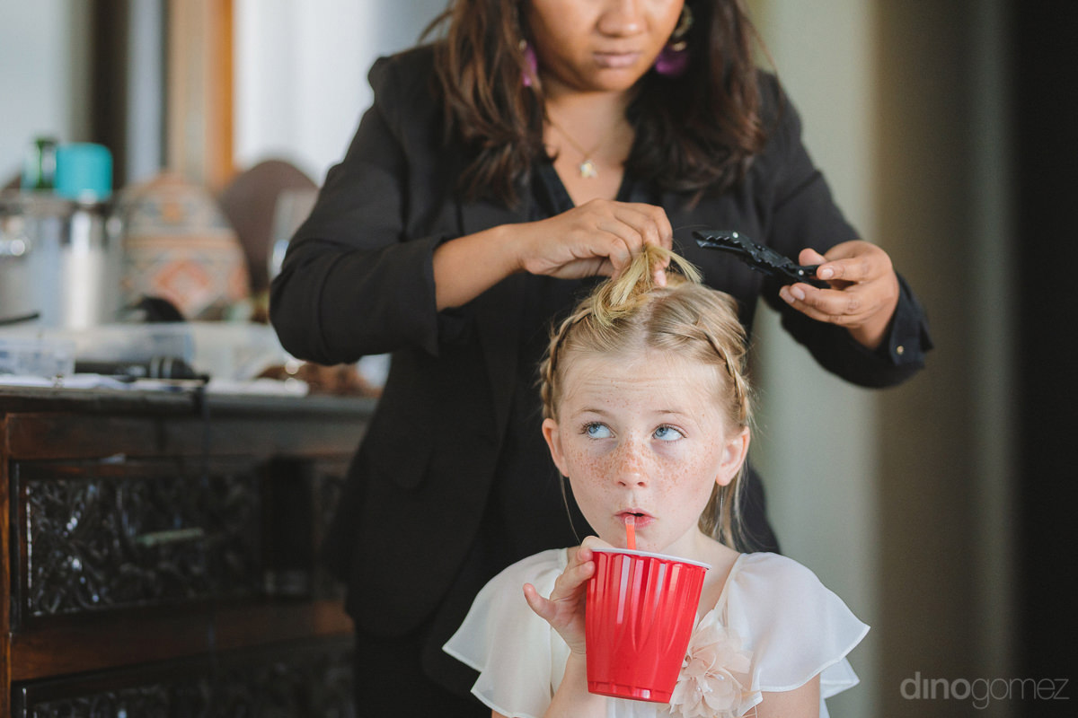 A Lovely Young Girl Can Be Seen Holding A Cup Of Drink And Sipping Through It While Getting Her Hair Done From The Artist For The Outdoor Wedding Of The Gorgeous Couple- Lara & Darrell