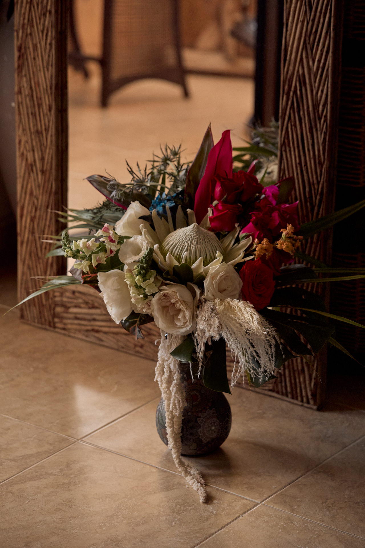 a vase filled with flowers sitting on top of a tiled floor.