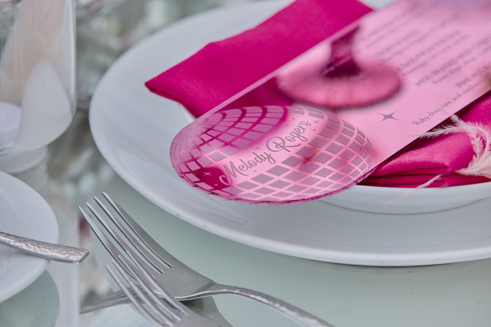 a table set with a pink and white plate and silverware.