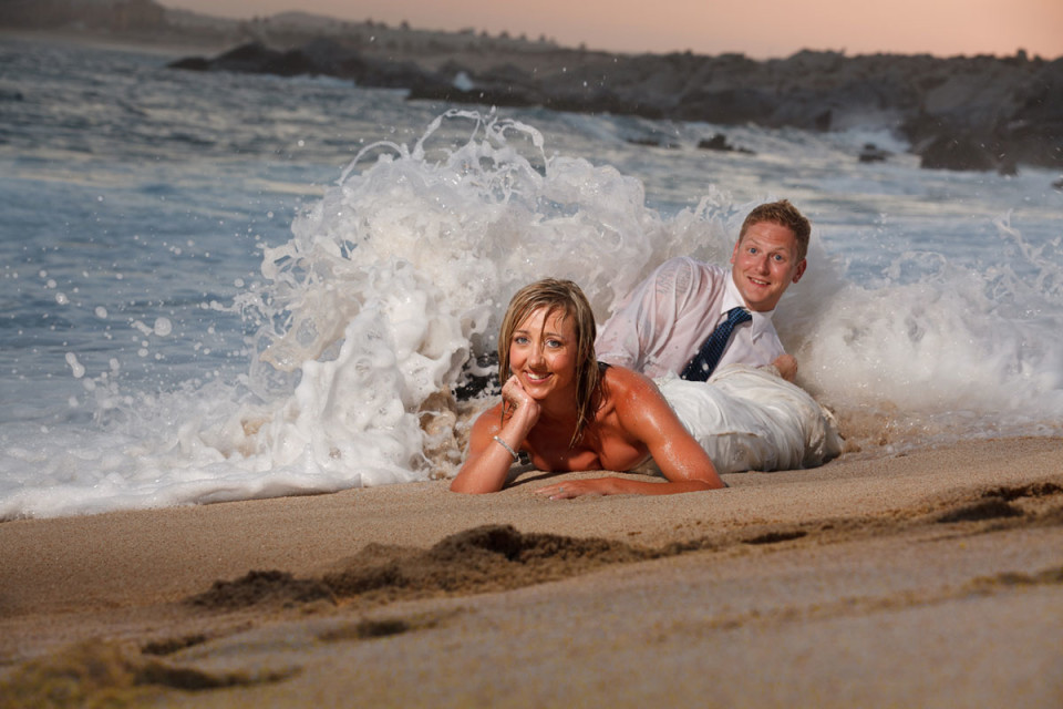 A gorgeous bride lying on her stomach with her groom on the shores in Mexico